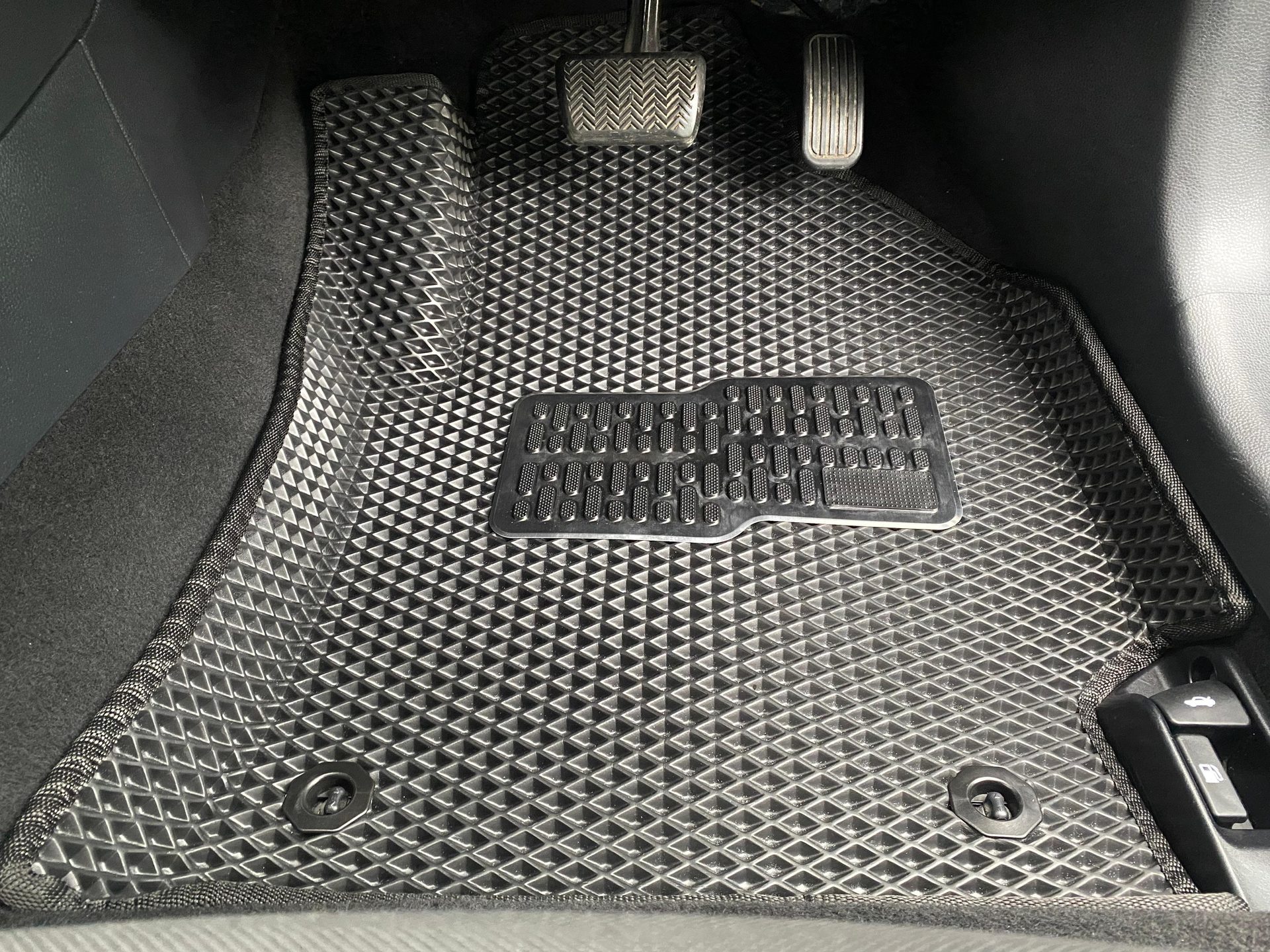 Black EVA mat with diamond texture fitted in a footwell